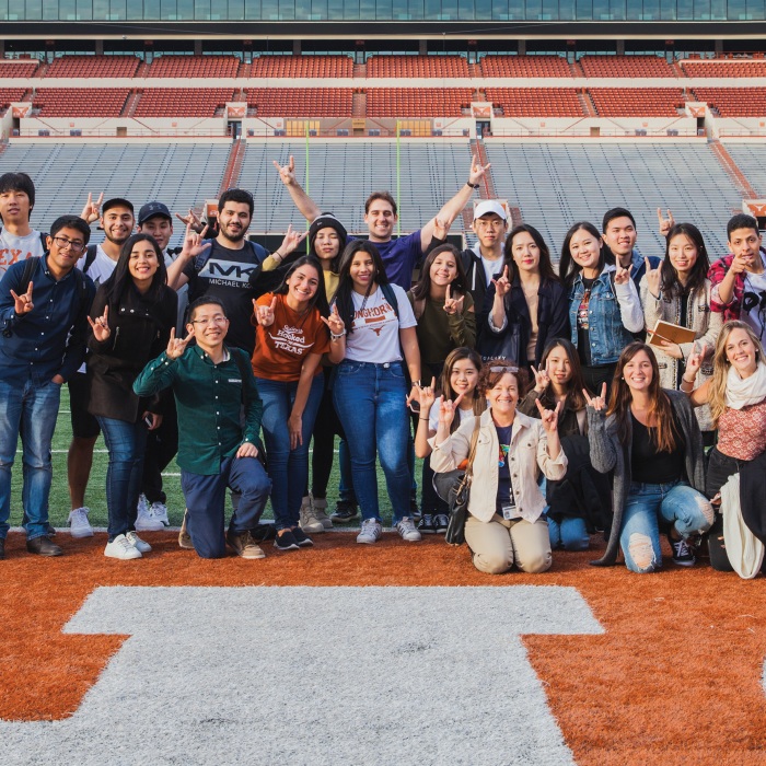 a group of students stands in the ut stadium
