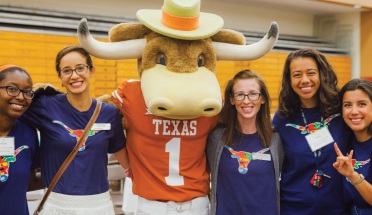 students stand with the hook em mascot at UT