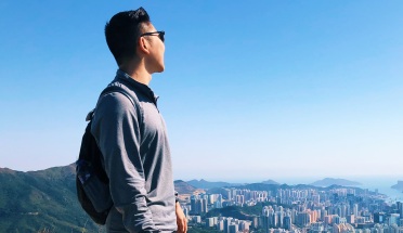 a student stands on a mountain overlooking a city in China