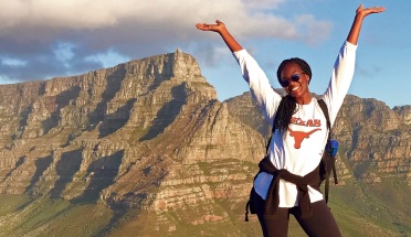 a student poses on a mountain and smiles