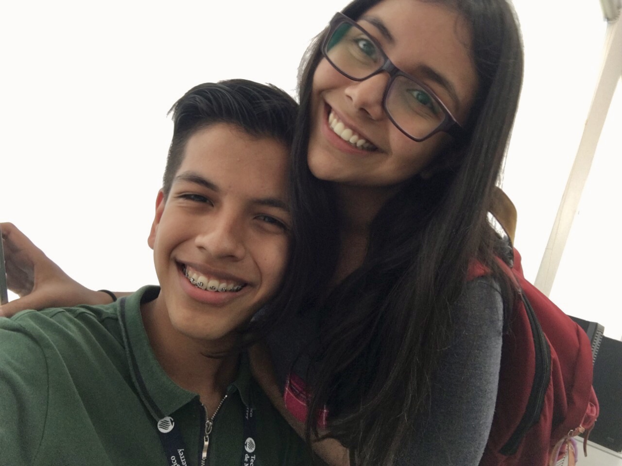 boy and girl wearing red backpack smile while taking a selfie