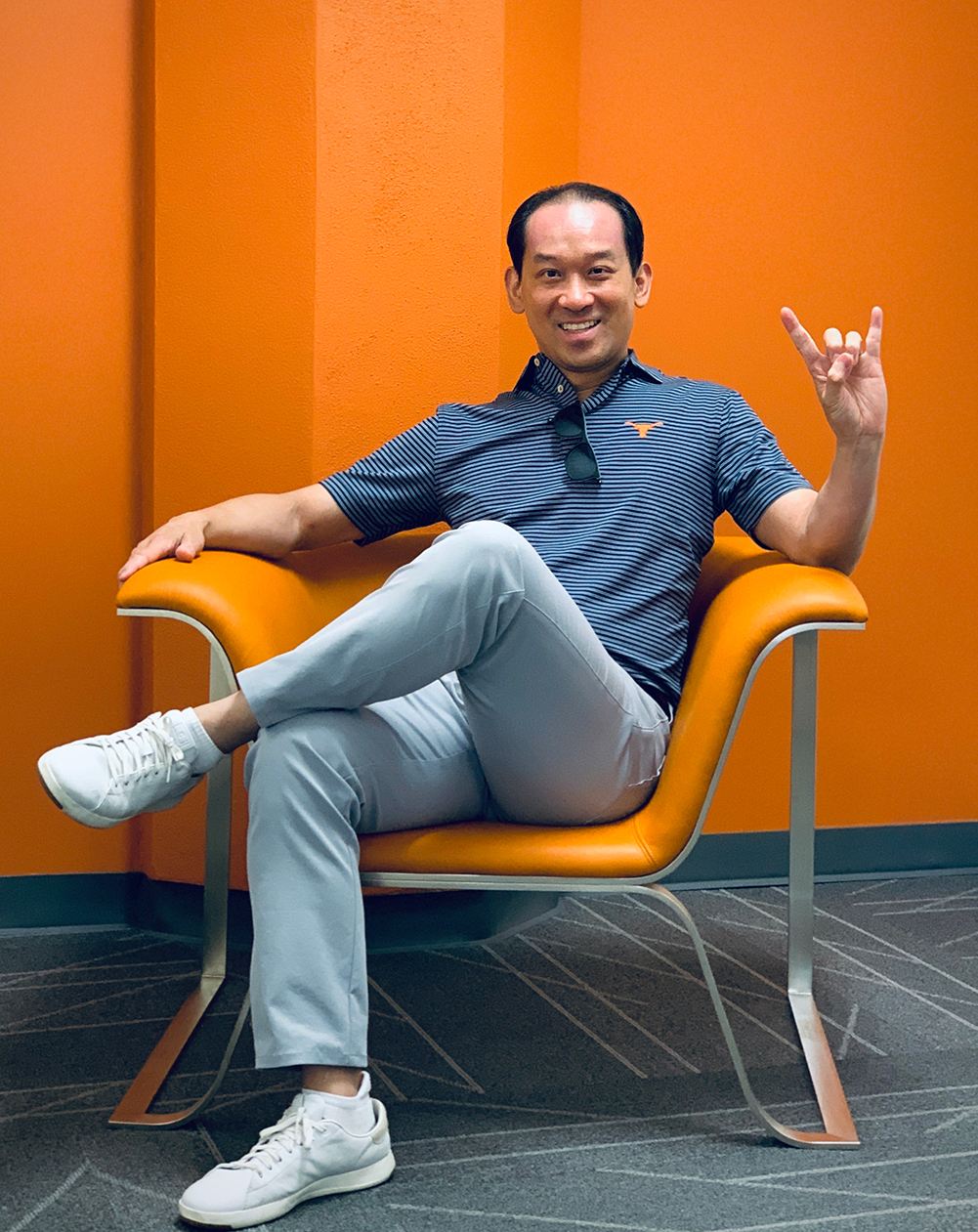 andrew vo poses in a burnt orange room and does a hook em