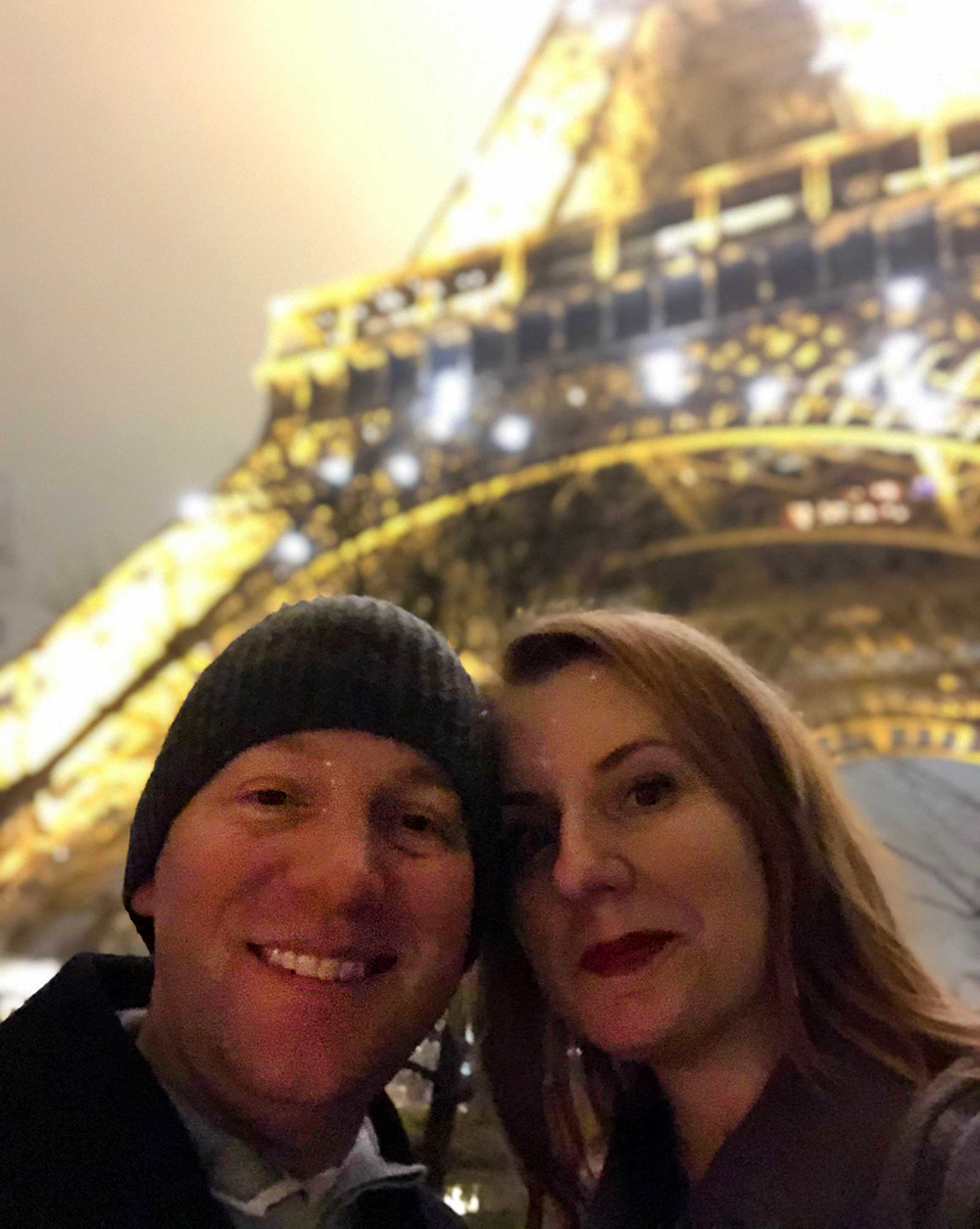 paul and his wife smile in front of the eiffel tower 