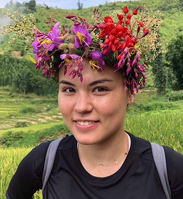 Kelsey wears a flower crown in front of a mountain in Singapore 