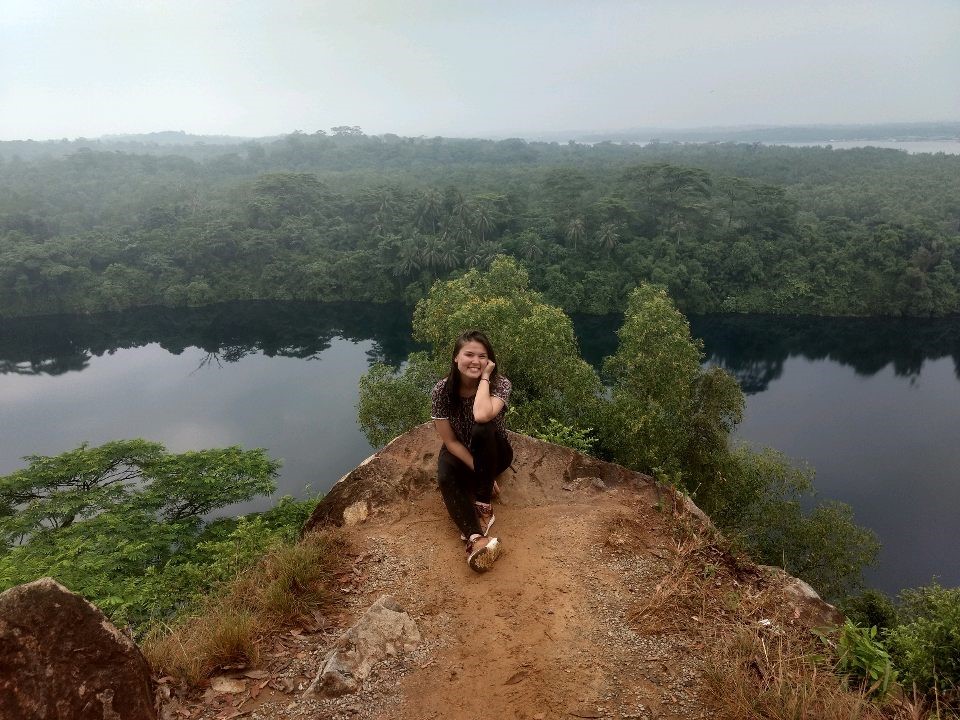 Kelsey sits on a cliff overlooking the water in Singapore