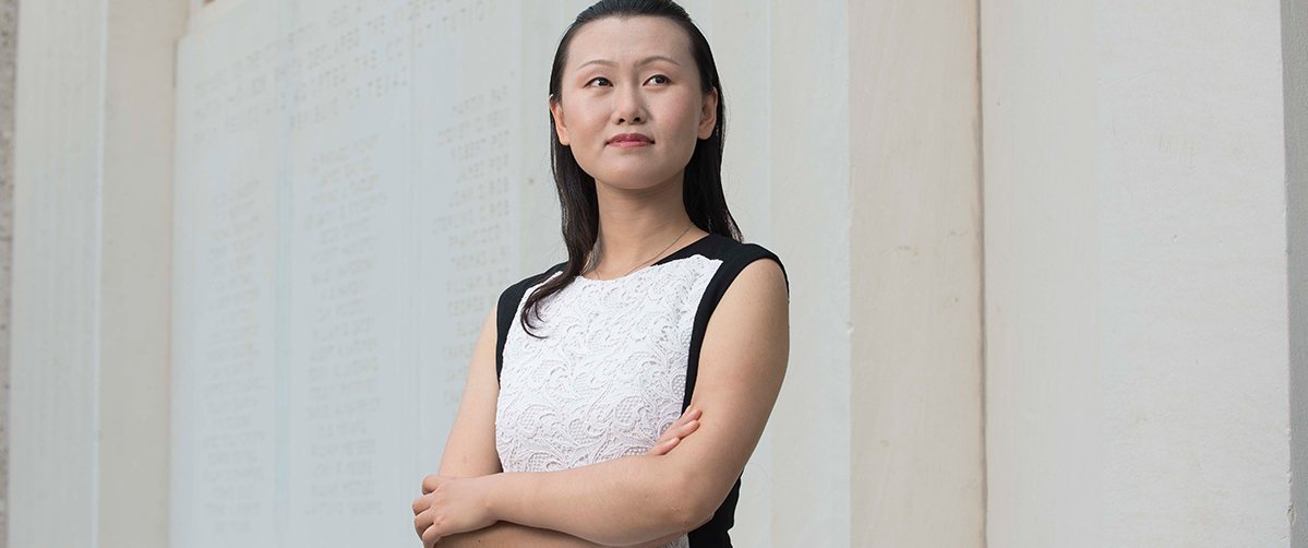 nanshu lu poses in front of a ut building