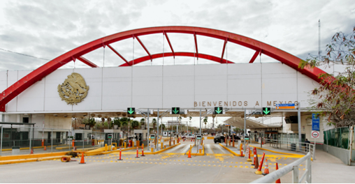 large immigration crossing with red arch and checkpoints
