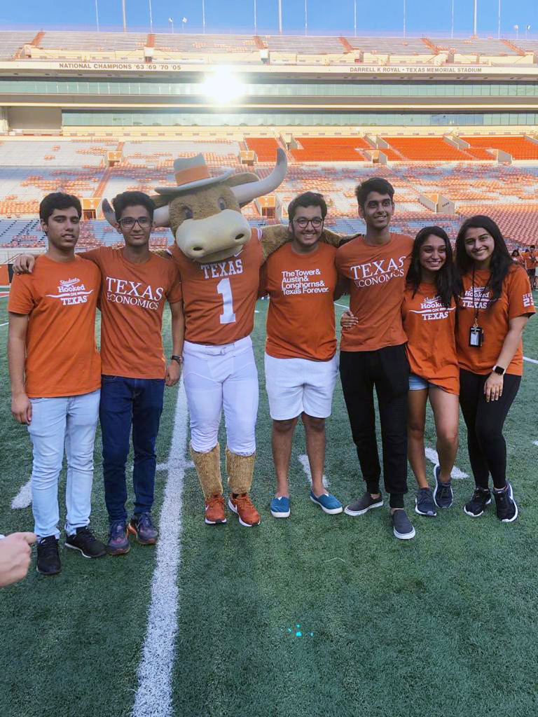 Bhalla and friends stand with Hook 'Em mascot on the UT football field.