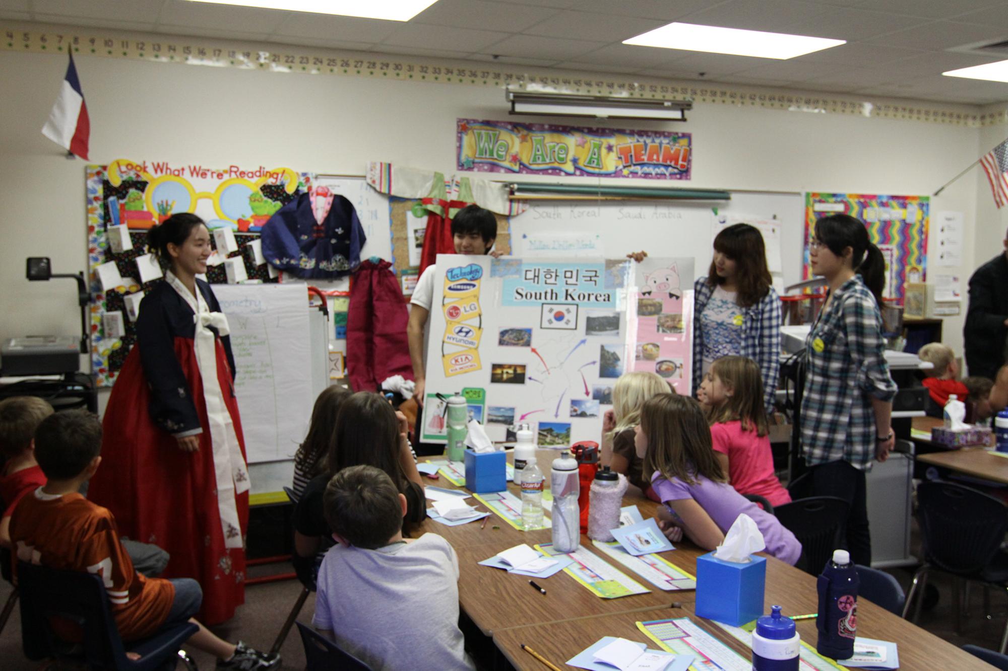 students present their board wearing traditional garb to classroom full of students