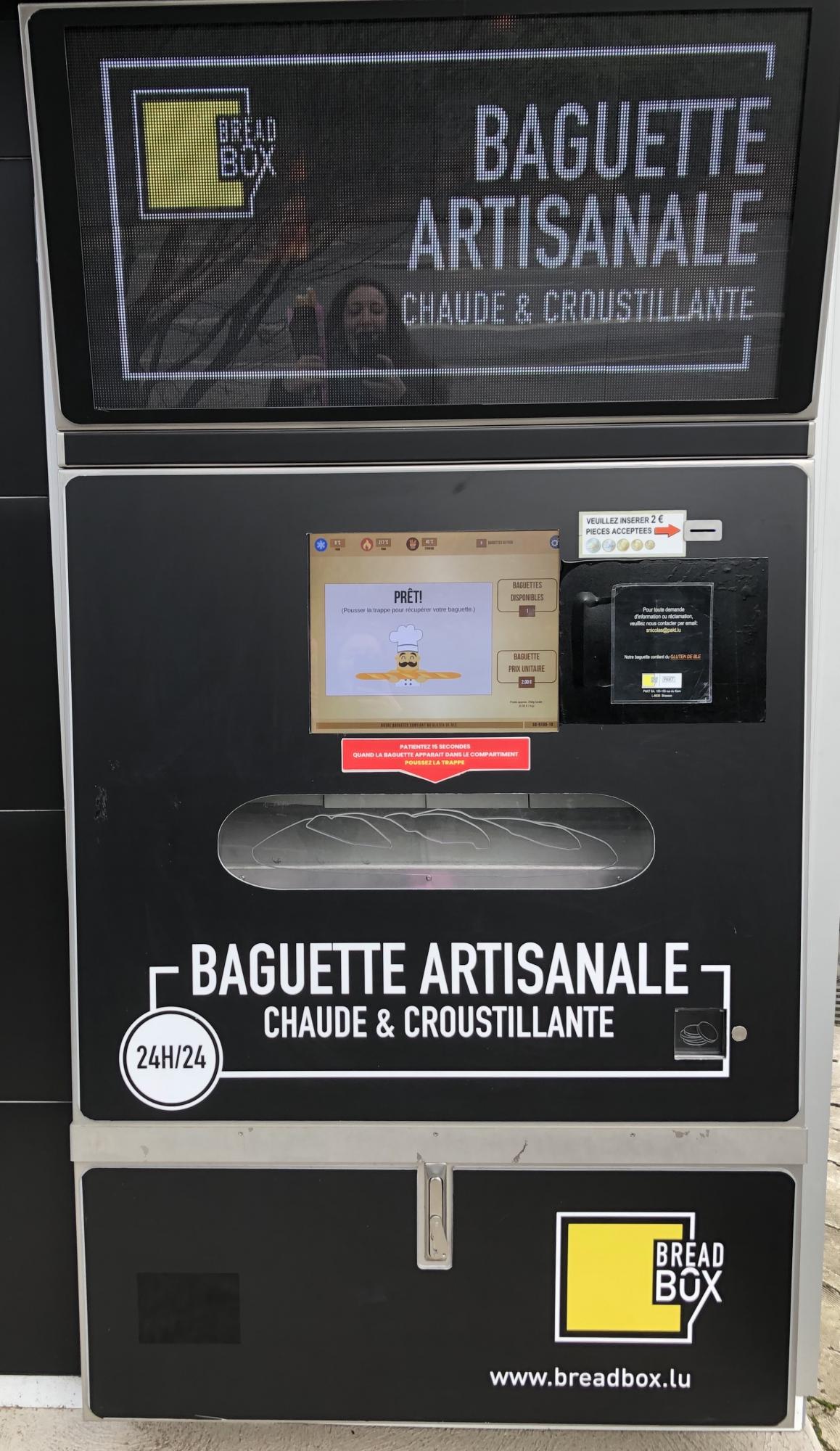 Frances Garnett reflected on surface of baguette vending machine