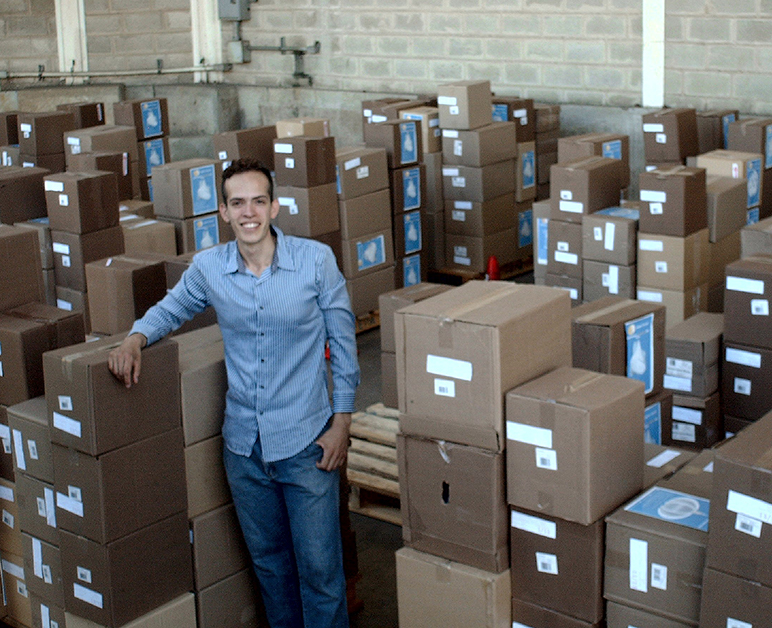 miguel poses in front of a warehouse of cardboard boxes 