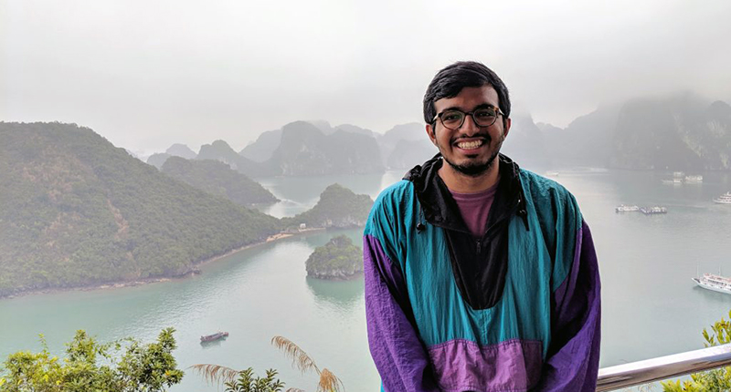avi poses in front of a mountain range and lake 