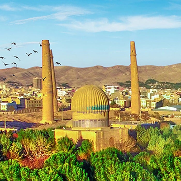 Afghanistan city with bright green trees and buildings in background