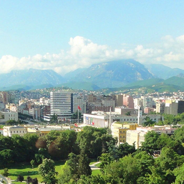 Albanian city with tall buildings and green trees