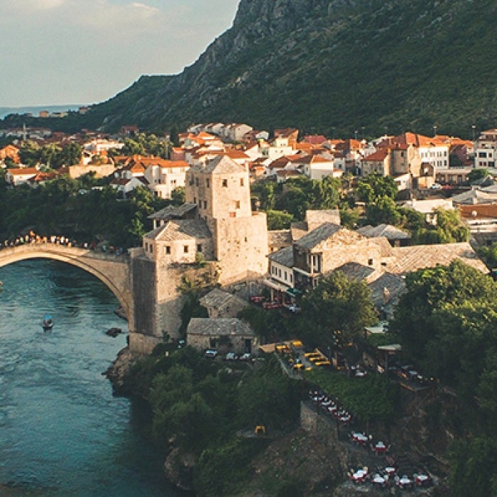 Two sides of Bosnian city connected by bridge with river in the middle