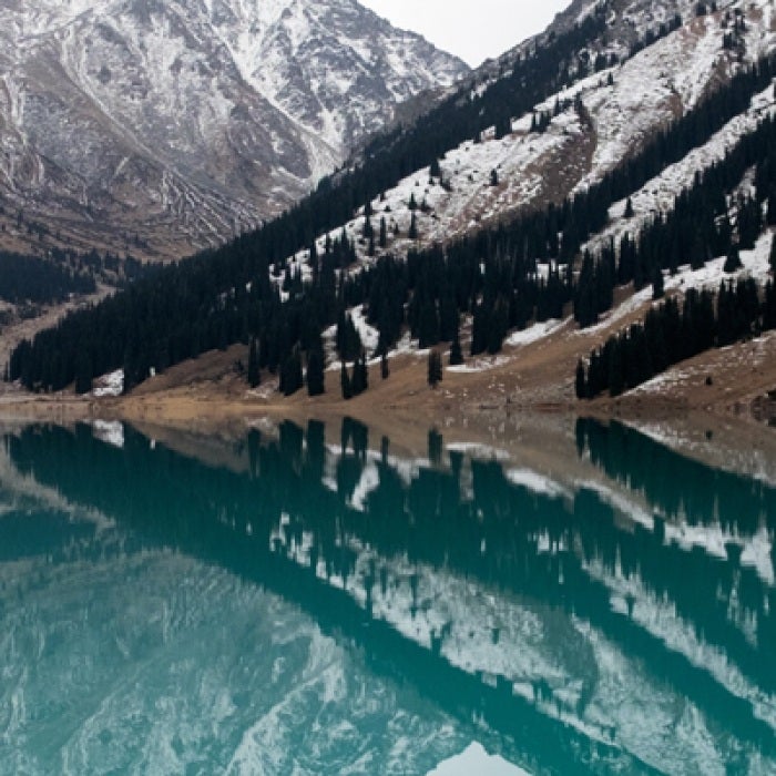 Kazakhstan lake with snowy mountains and trees
