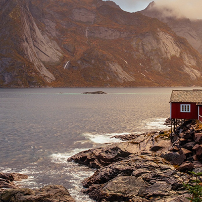 Norway traditional red house on rocks by water