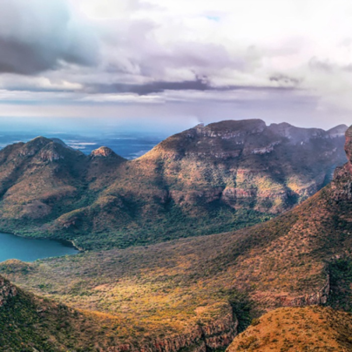 South African mountain range with river on the left and clouds in the sky