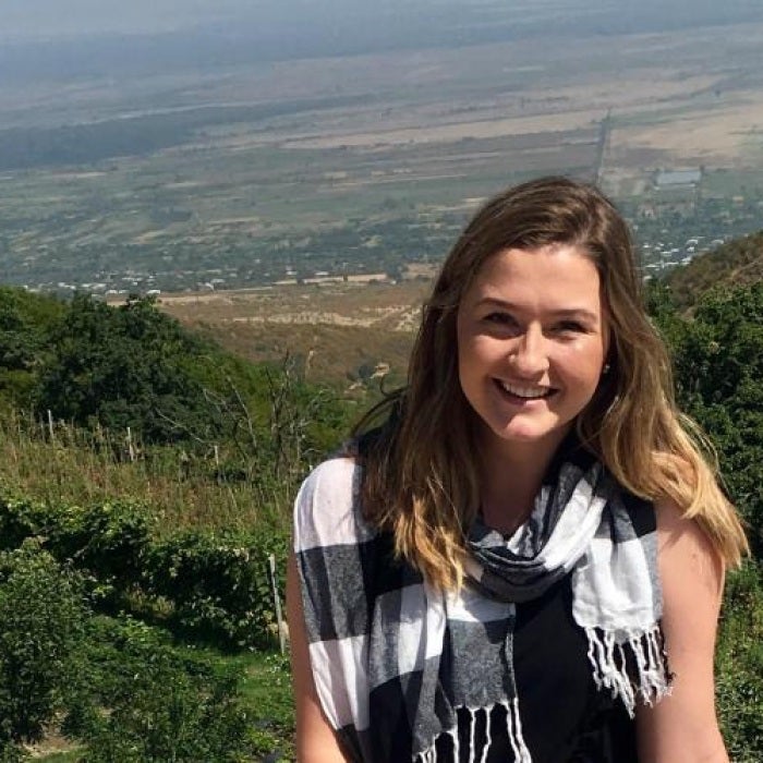 UT studen smiles for the camera with a green hill behind her 