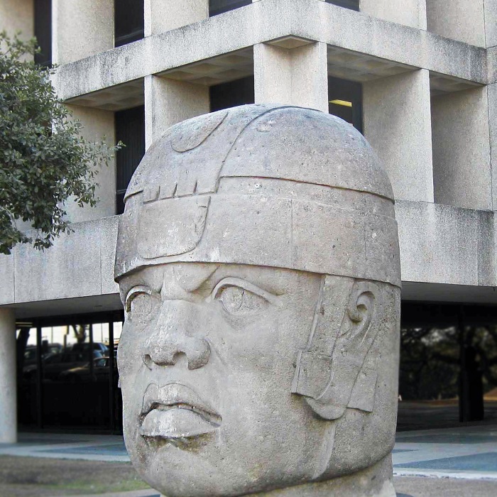 the olmec head statue in front of a building on campus