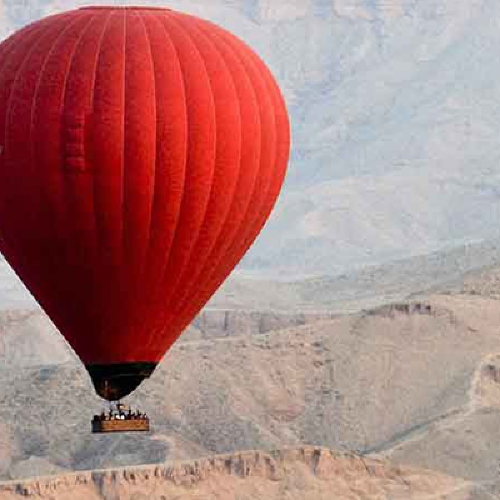 A red hot air balloon hovers in the sky in Egypt. 
