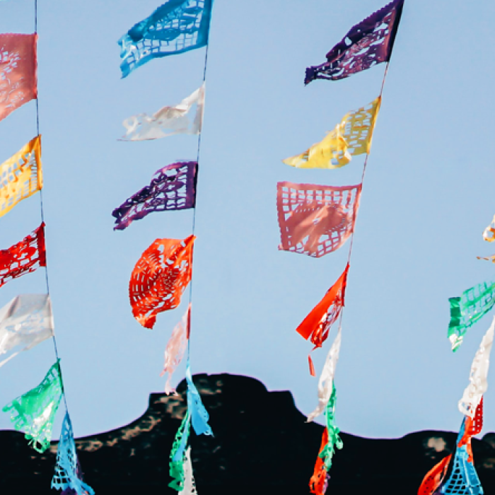 Colorful flags strung together against a blue sky backdrop.