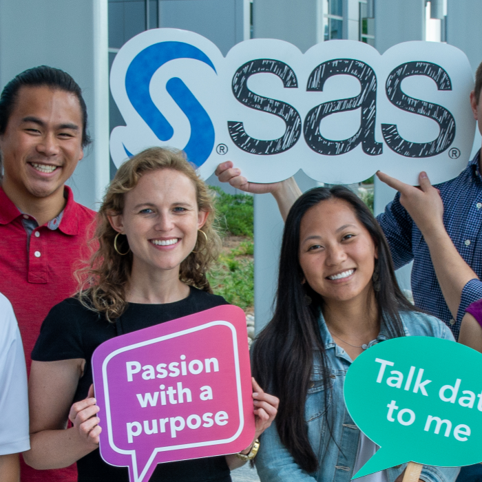 group of people hold signs with company logo and phrases near building during daytime