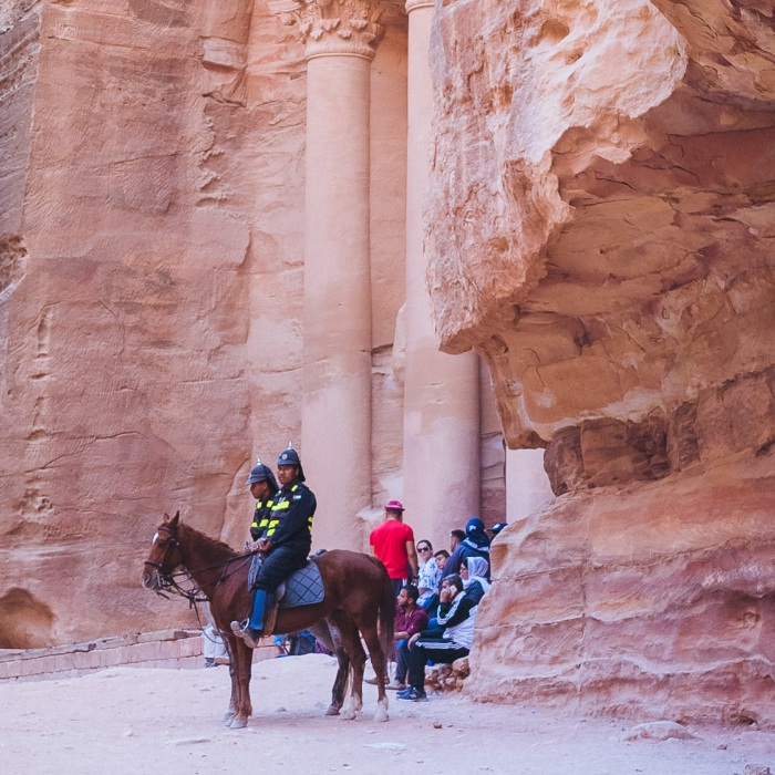 group of people riding horse beside rock formation