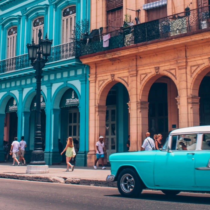 blue and white vintage care parked near colourful buildings with arches