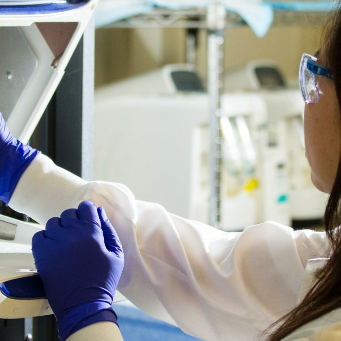 a scientist wearing gloves in a lab and using test tubes 
