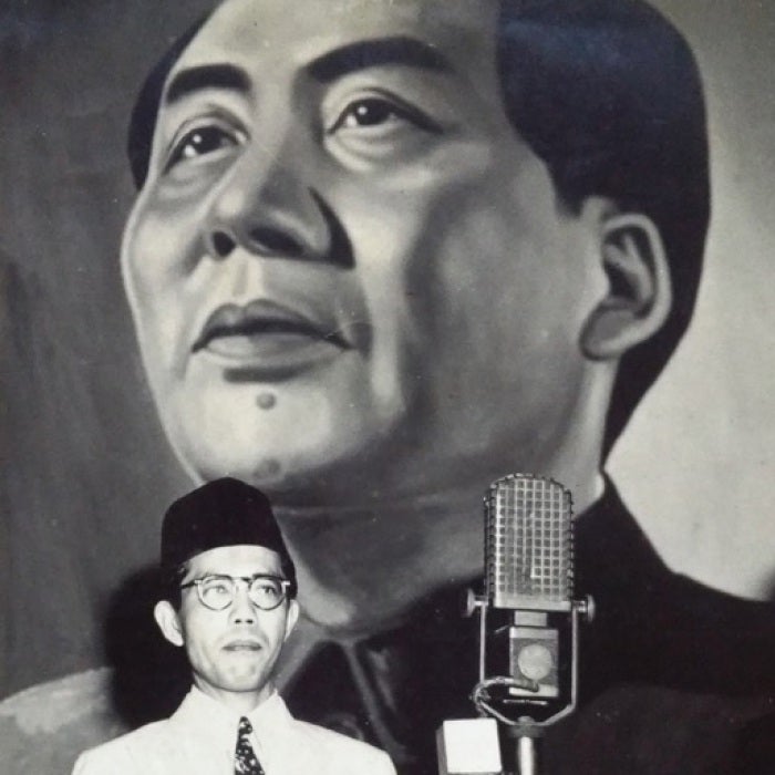 three men stand in front of large banner with picture of man's face and stars