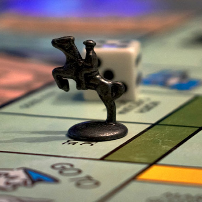 Image of Monopoly game horse and rider game piece on Monopoly board. 