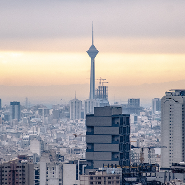 Tehran's dense cityscape with a rising sun behind. 
