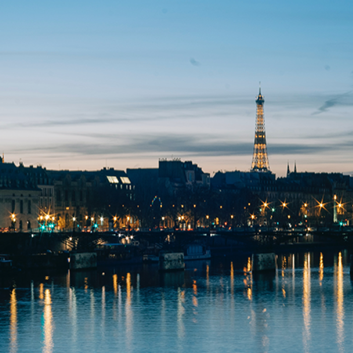 Dusk view of the Eiffel Tower and surrounding river and village in Paris, France.