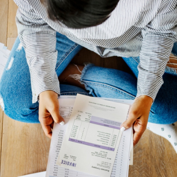 woman sitting on floor surrounded by bills and bank statements