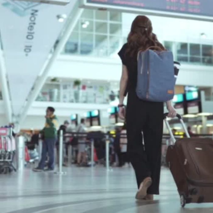 student with suitcase walking through airport