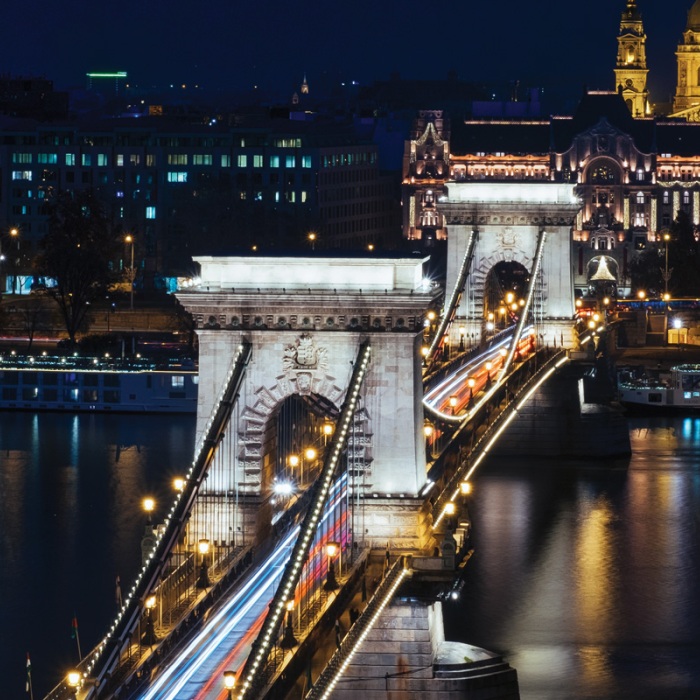 European bridge and architecture lit up at night during a long exposure over a river