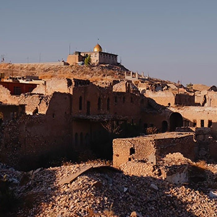 country landscape in Iraq showing demolished buildings with mosque in background 