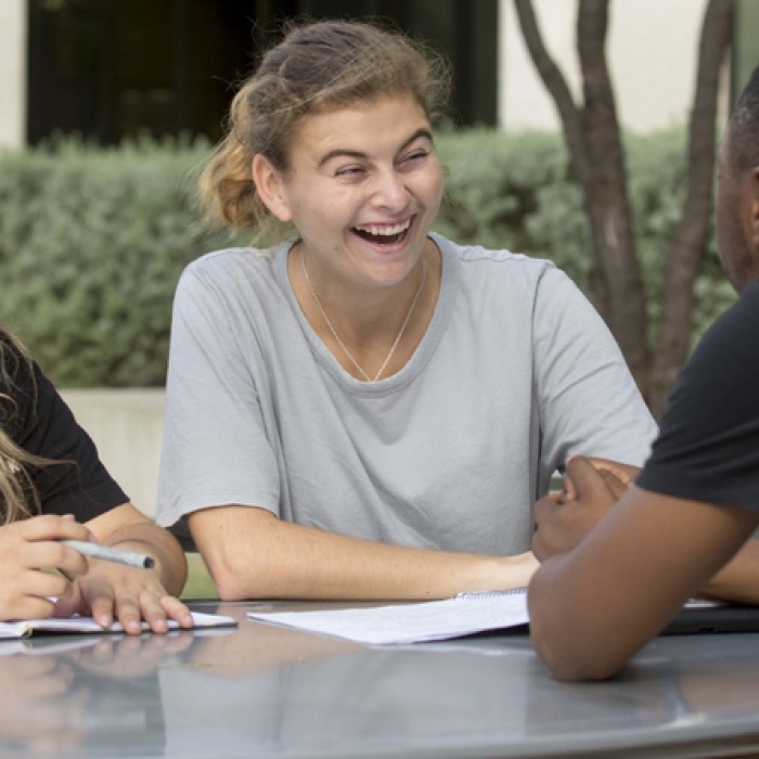 Students laughing in conversation at table outside