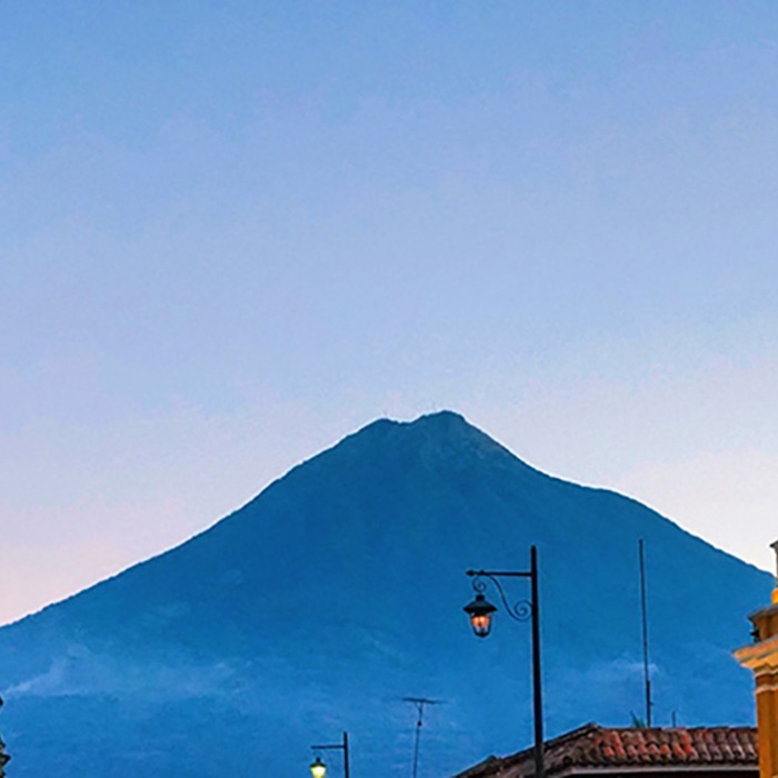 Historic buildings in foreground frame a distant mountaintop in Guatemala