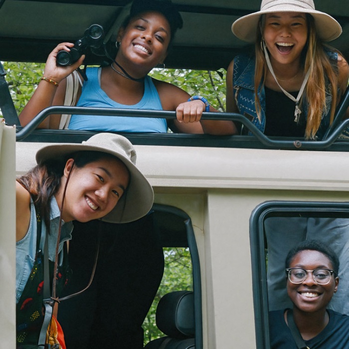 Diverse students participants smile and pose from a jeep in the jungles of Ghana Africa