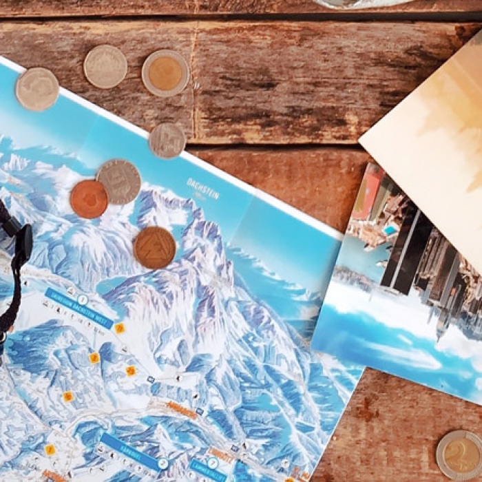 travel imagery, a film camera, and foreign currency scattered over an aged wood table