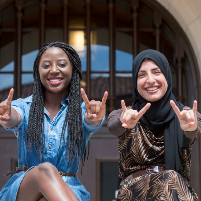 Group of students holding up the hook'em hand sign