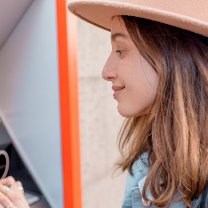 woman in hat using ATM