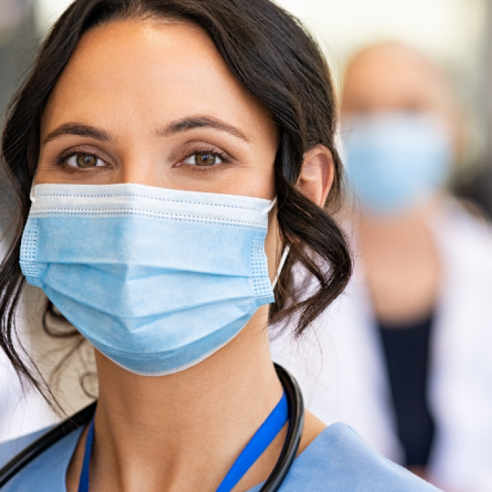 Nurse wearing mask with doctors and nurse in background