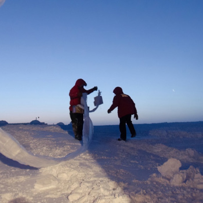 Researchers launching weather balloons in Antarctica at dusk