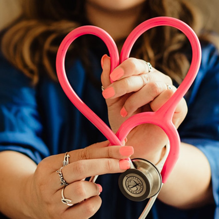 a doctor holds a stethoscope in the shape of a heart