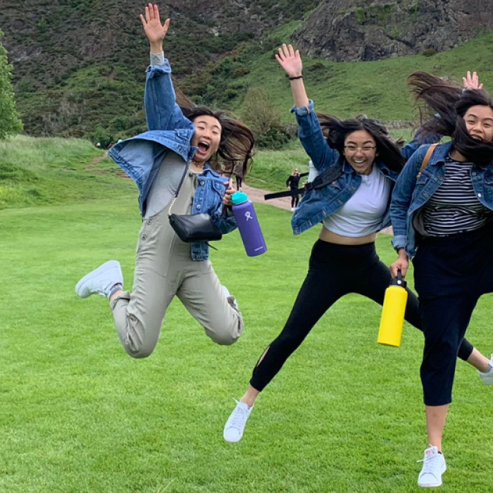 Students jumping with their arms outstretched in a field