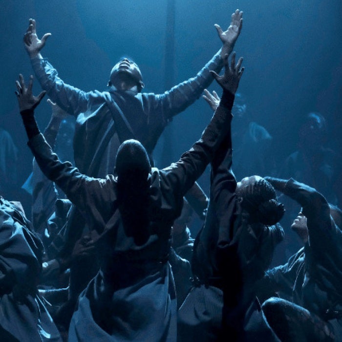 A group of dancers performing on a dimly lit stage