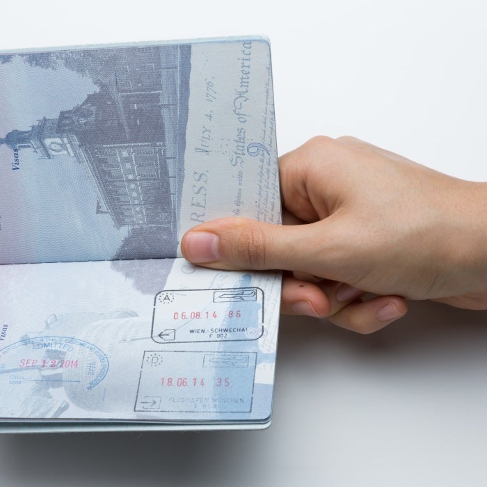 Hand holding an open passport with entry stamps